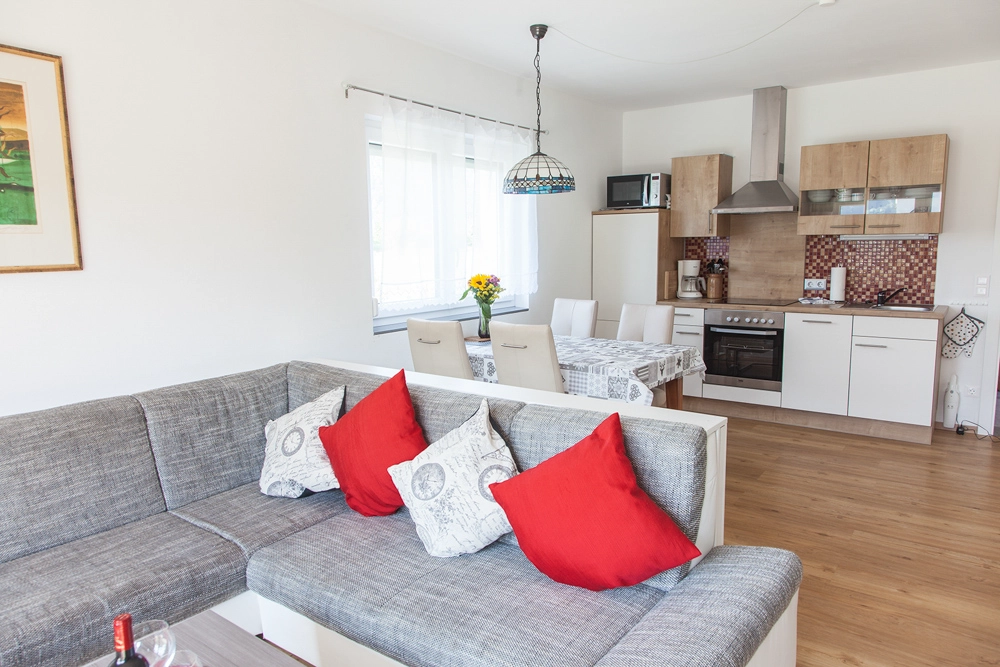 „Hahns Herberge“ – Blick vom Wohnzimmer auf die Wohnküche - Möblierter Innenraum, professionelle Immobilienfotografie.